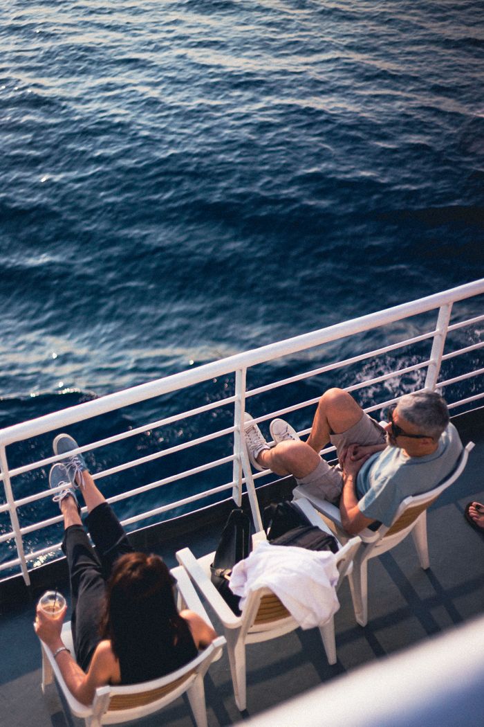 about-us-02 Couple relaxing on a cruise ship deck, enjoying the serene ocean view on a sunny day.